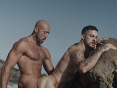 Appealing men fuck by the rocks in outdoor threesome and share great details