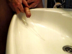 John is peeing into the bathroom sink