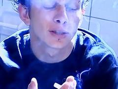 Twink smokes on the toiled while stroking his hard cock