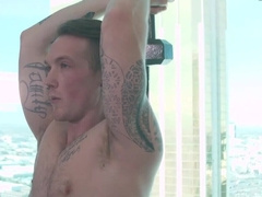 Tattooed man works out with weights and a submissive fella
