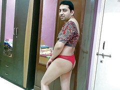 Sexy sissy crossdresser femboy Sweet Lollipop in a printed top, red thong and satin slippers.