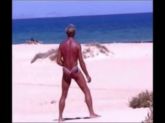 Suntanned boy on beach in little strap g-string temporarily