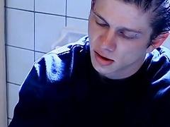 Twink smokes on the toiled while stroking his hard cock